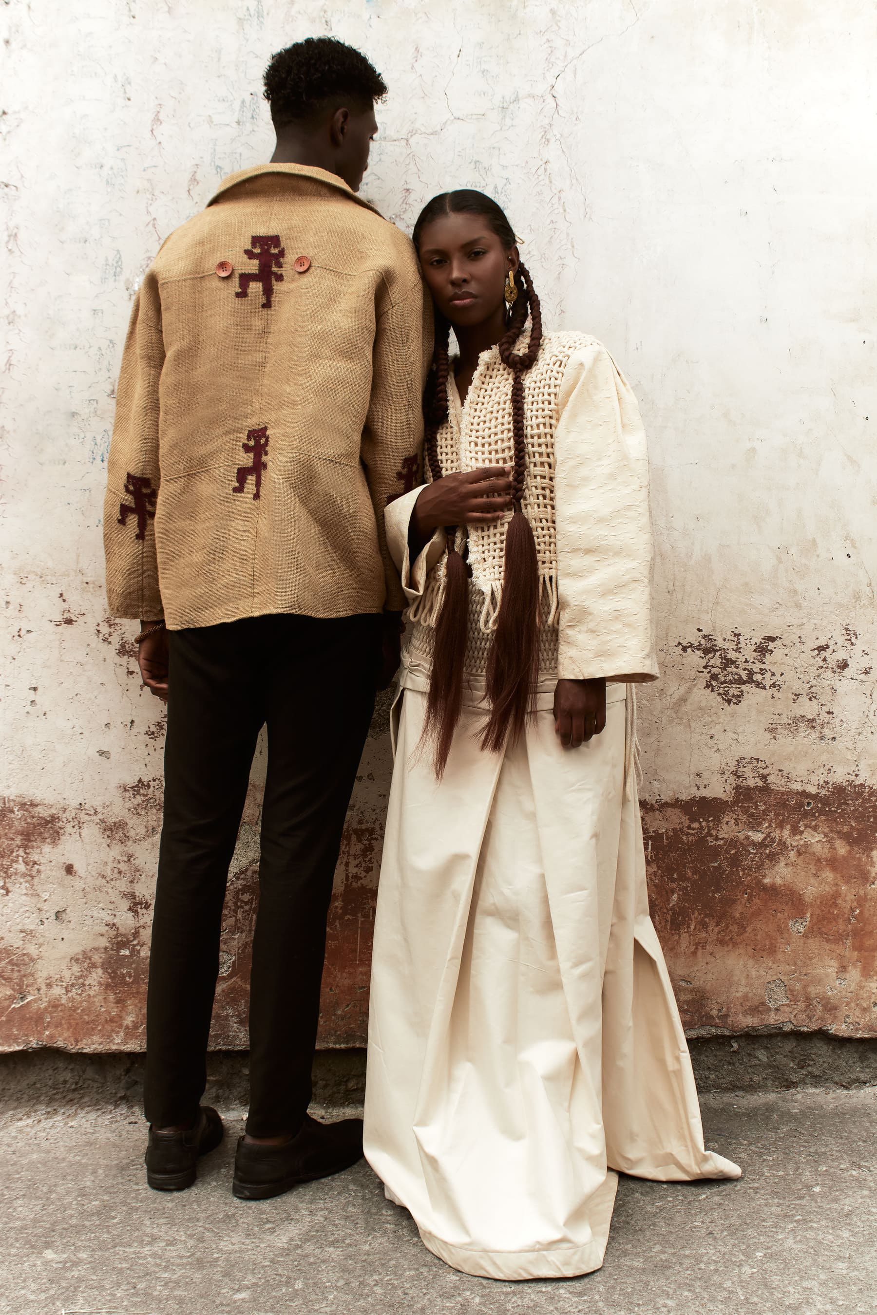 Editorial Coangue: pareja de modelos con prendas artesanales bordadas junto a un muro texturizado.