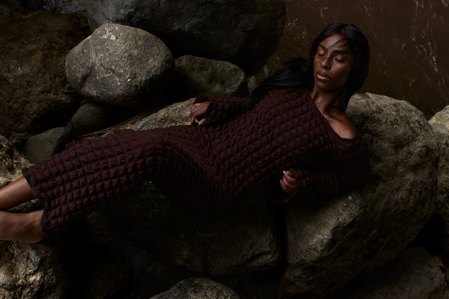 Editorial Coangue para Harper's Bazaar Ecuador: modelo recostada entre rocas junto al río.