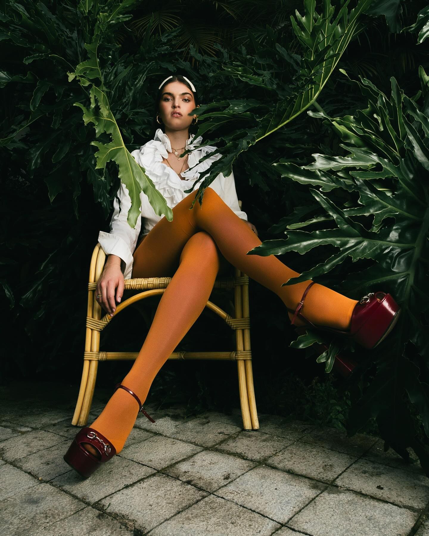 Editorial InStyle Grecia: modelo junto a una piscina con blazer negro y medias naranjas.