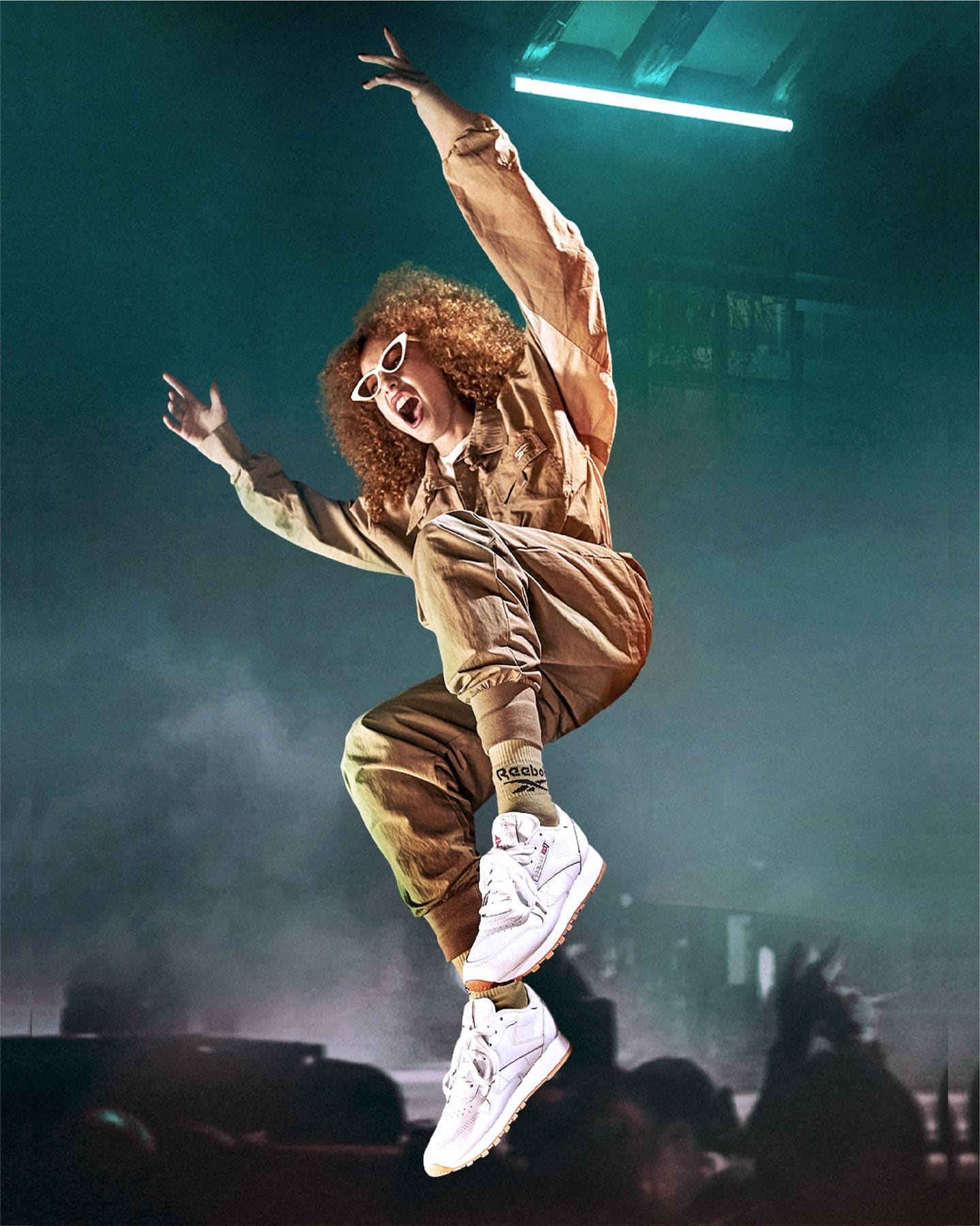 Campaña Reebok: modelo saltando con zapatillas blancas sobre fondo verde con niebla.